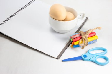 arka planda not defteri ve renkli boya kalemleri.