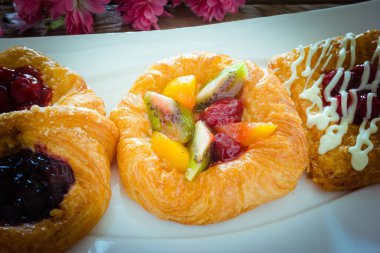 Beyaz tabakta meyveli Danimarka çöreği.