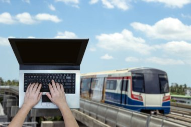 Bulanık tren arkaplanı olan dizüstü bilgisayar kullanan kadın