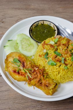 Ahşap arka planda pişmiş zerdeçal yaseminli tavuk biryani.