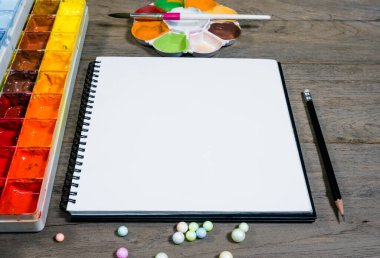 Ahşap zemin üzerinde tepsi renkleri olan açık not defterini kapat