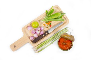 Arka planda kesim tahtası ve sebzeli domates soslu uskumru.