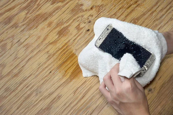 Hände Halten Weißes Tuch Mit Nassen Smartphone Tropfen Auf Holzboden — Stockfoto