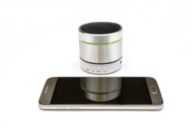 cep telefonu ve gümüş bluetooth hoparlörü beyaz arkaplanda izole edildi