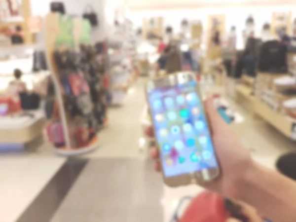 ショッピングモールで携帯電話を手に取り背景をぼかす — ストック写真