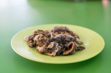 Yeşil tabakta kızarmış balık derisi.