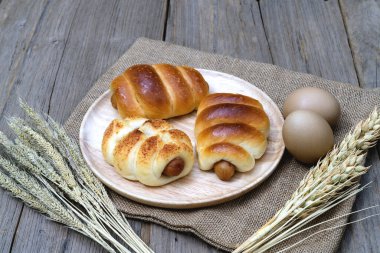 Sosisli ekmek ve buğday kulakları ve tahta arka planda çuval..