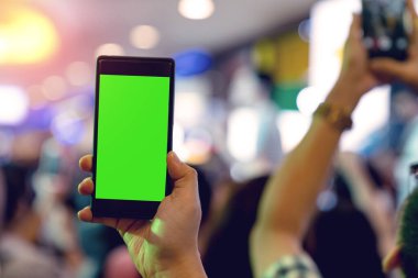 Küçük konser arka planında ışık saçan cep telefonu tutan eller