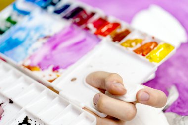 Yakın plan renkli paleti tutan el.