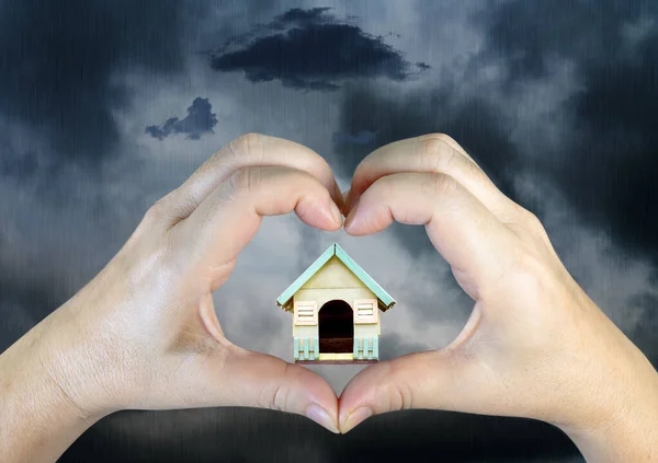 人的手在雨云的背景上造出木制房子的心形 — 图库照片