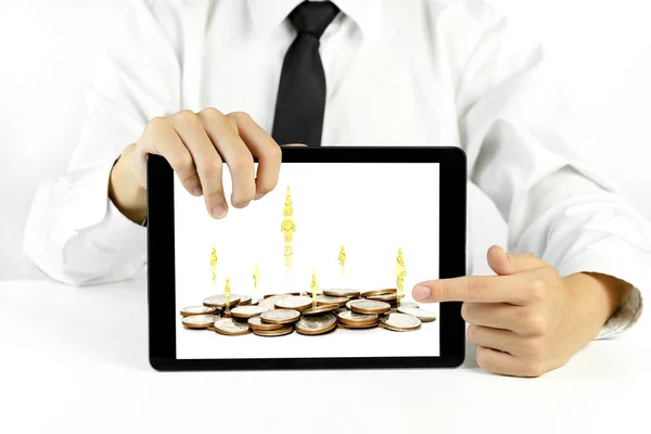 Businessman holding a tablet with coins and chart of indicators in business,economic growth concept
