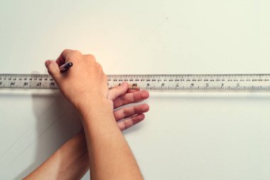 El ele tutuşan cetvel ve debriyaj tipi arka planda tuval olan kalem