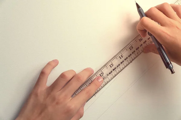 hand holding ruler and clutch-type pencil with canvas background