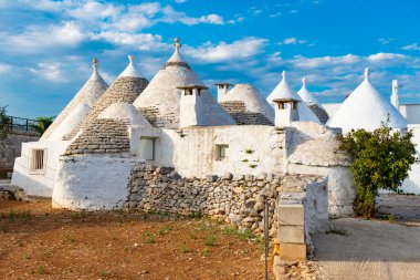 Bir grup güzel beyaz Trulli, Puglia, İtalya 'da geleneksel eski evler, market bahçesi ve taze domatesleri var.