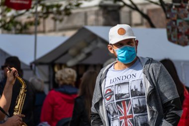 Man wearing mask with London, UK flag t-shirt. Prime Minister announced new Coronavirus, Covid restrictions for England, including earlier pub-closing times clipart
