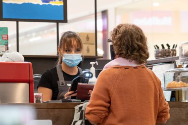 Vilnius, Litvanya - 28 Eylül 2020: Covid veya Coronavirus ikinci dalga salgını sırasında kapalı bir barda, kafede, fast food veya restoranda müşteriye hizmet eden maske ve eldivenli güzel garson