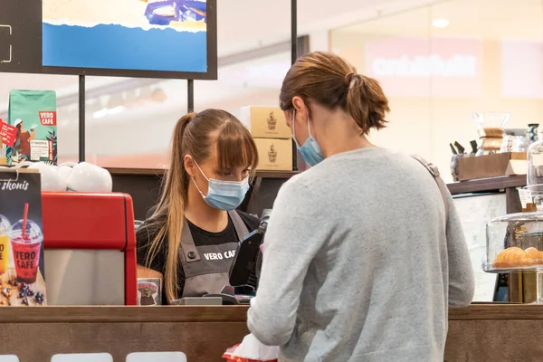 Vilnius, Litvanya - 28 Eylül 2020: Covid veya Coronavirus ikinci dalga salgını sırasında kapalı bir barda, kafede, fast food veya restoranda müşteriye hizmet eden maske ve eldivenli güzel garson