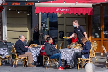Vilnius, Litvanya - 12 Ekim 2020: Covid veya Coronavirus salgını sırasında bir açık hava barında, kafede veya restoranda yemek servisi yapan maskeli garson, ikinci dalga 