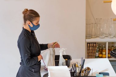 Vilnius, Litvanya - 12 Ekim 2020: Coronavirus ya da Covid salgını sırasında barda, kafede ya da restoranda maske temizliği ve dezenfekte maskesiyle güzel bir garson