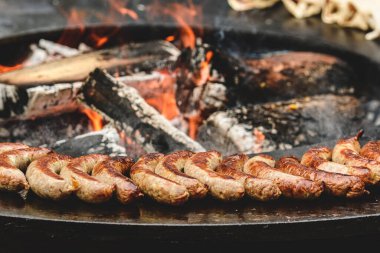 Ahşap odunlar ve parlayan közlerle açık ateş çukurunda pişen ızgara sosisler. Köy düzeni açık hava yemekleri ya da geleneksel barbekü öneriyor.