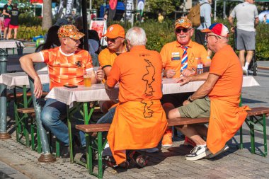 Vilnius, Litvanya - 7 Eylül 2025: Turuncu giyimli Hollandalı futbol taraftarları Hollanda maçından önce halka açık bir alanda birlikte oturup içki içiyorlar 