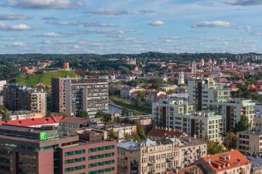 Vilnius şehri, Litvanya 'nın Gediminas Kalesi Kulesi ile çevrili yeşil bir tepe üzerinde yerleşim yerleri, ağaçlar, Neris nehri ve bulutlu mavi gökyüzü.