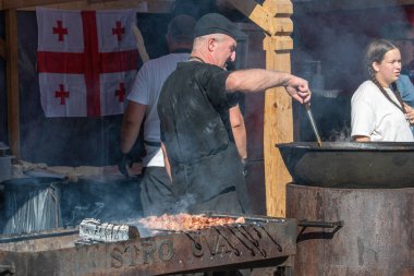 Vilnius, Litvanya - 21 Eylül 2025: Sokak gıda tedarikçisiyle Gürcistan mutfağı et şişleri pişiriyor ve açık hava gıda festivalinde büyük bir tencerede yemek pişiriyor