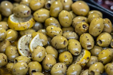 Limon dilimleri ve bitkilerle marine edilmiş yeşil zeytin. Geleneksel Akdeniz aperatifleri ve baharat ve zeytinyağıyla tatlandırılmış atıştırmalıklar. Taze ve sağlıklı gurme yemekleri.