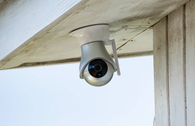 Evin duvarında kablosuz internet antenli kirli bir evin tavanında 360 derece siyah mercekli küçük gümüş ve beyaz güvenlik kamerası baş aşağı asılı..