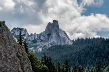 Bulutlu gökyüzünde yeşillikle kaplı güzel bir dağ manzarası.