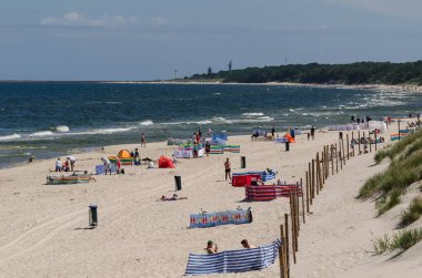 KOLOBRZEG, BATI POMERANYA / POLAND - 2020: İnsanlar güvenli mesafeleri korurken güneşli deniz sahillerinde dinleniyorlar