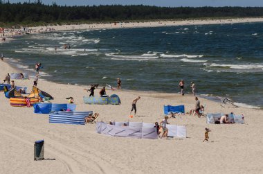 KOLOBRZEG, BATI POMERANYA / POLAND - 2020: İnsanlar güvenli mesafeleri korurken güneşli deniz sahillerinde dinleniyorlar