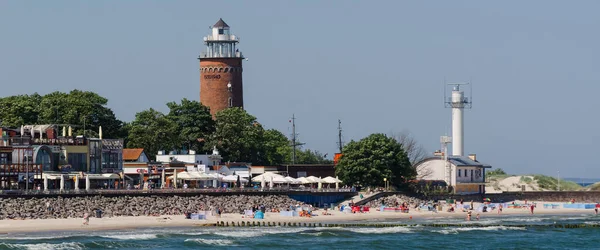 KOLOBRZEG, BATI POMERANYA / POLAND - 2020: Plajda tatil turistleri ve deniz fenerinin önündeki gezinti alanı