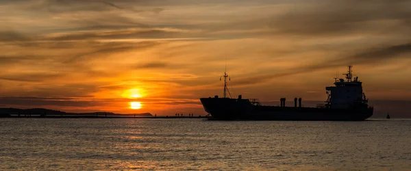 SUNSET BY THE SEA - An evening landscape by the sea coast and a ship going to the port