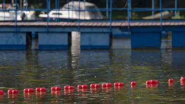 Göl kıyısında dinlenme - Arka planda Marina ve ön plandaki yüzme alanında güvenli şamandıra hattı