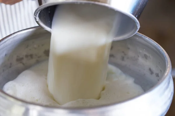 İşçi dönüşüm için sütü bir kabın içine boşaltıyor.