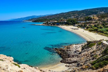 Ikaria adasındaki Livadi 'deki Yunan Ege Denizi Sahili' nde sakin bir yaz günü, bembeyaz mavi sularla dolu. Ermenilerin Yakınları
