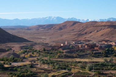 Beyaz kar ve vahadaki yeşil çimlerle karıştırılmış çöl. Ait Ben Haddou 'nun yanındaki Atlas Dağları ve Sahra Çölü' ndeki Berberi kasabaları.
