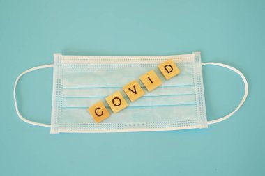 Mavi tıbbi tek kullanımlık yüz maskesi. Mavi arka planda, grip, virüs, bakteri ve diğer hastalıklara karşı korunmak için kullanılan mavi renkli kelimelere sahip. Cerrahi koruyucu maske.
