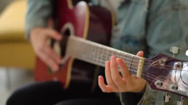 Genç bir kadının gitar çalmasını ve öğrenmesini yakından takip et.