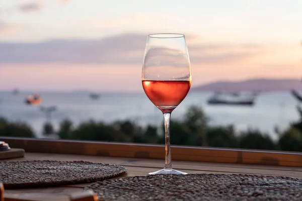 Singolo Bicchiere Vino Rosato Sfondo Naturale Mare Cielo Colorato Alberi — Foto Stock