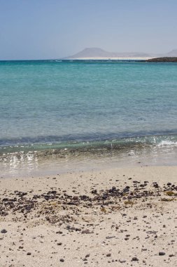 Sahildeki taşlar Lobos Adası Corralejo, Fuerteventura 'da kırılıyor. Dalgalar çakıl taşlarıyla kumlu bir sahile vuruyor.