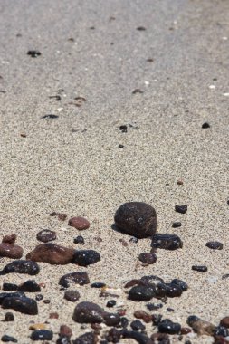 Lobos Adası Corralejo, Fuerteventura 'nın arkasında hafif sakin dalgaların olduğu kumlu bir sahilde volkanik çakıl taşları. Metni kopyalamak için boşluk.