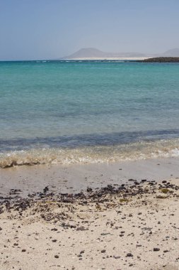 Sahildeki taşlar Lobos Adası Corralejo, Fuerteventura 'da kırılıyor. Dalgalar çakıl taşlarıyla kumlu bir sahile vuruyor.