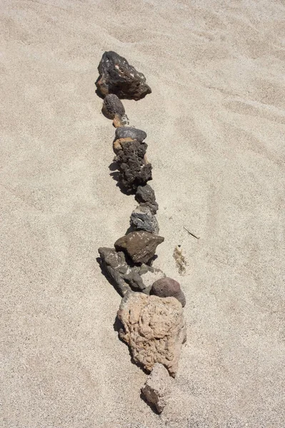 Line of stones in the sand. Collection of volcanic stones lined up in the sand. Lobos Island Corralejo, Fuerteventura