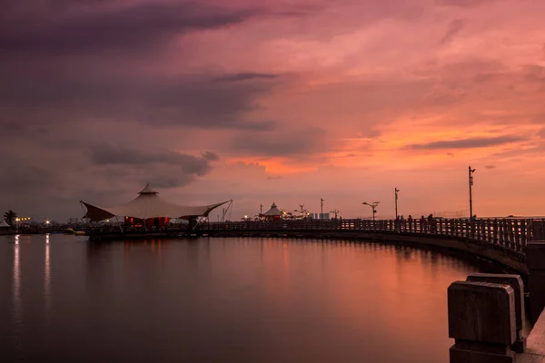 Ancol Beach, Kuzey Jakarta 'da bulutlu turuncu gökyüzü ile güzel bir gün batımı.