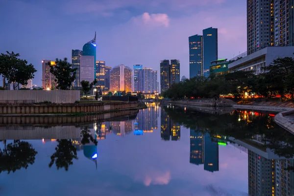 Gün batımında güzel bir Jakarta şehri. Jakarta 'nın ofis inşaatı ve iş merkezinin manzarası akşam vakti suya yansıdı
