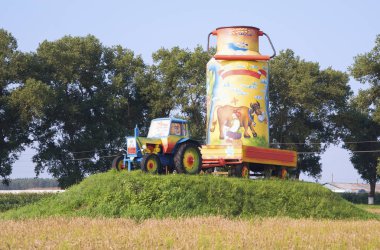 Köyde bir tepe üzerinde bir karavanda neşeli traktör büyük süt ile olabilir boya dekore edilmiş.