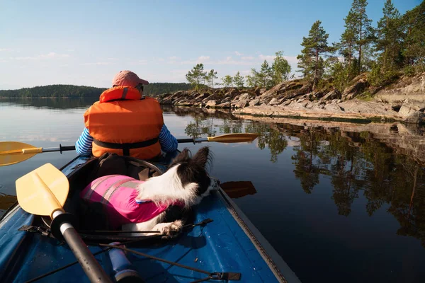The owner and the dog in a life jacket floating in a kayak boat. — Stock Photo, Image