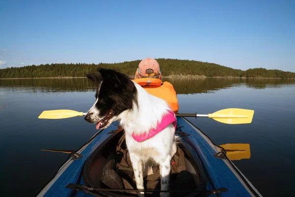 O dono e o cachorro em um colete salva-vidas flutuando em um barco de caiaque . — Fotografia de Stock
